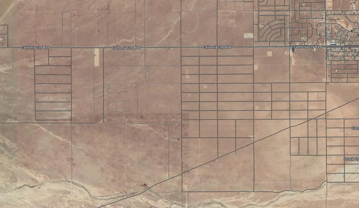 Satellite view of a desert area with a sparse grid of roads and plots labeled